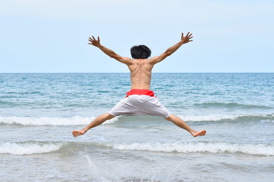 A man jumps in ocean waves. Jump with splashing water Summer Sunny Day