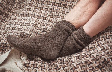 Man feet on woolen plaid in woolen socks