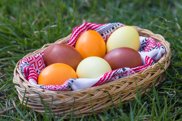 Unique hand painted Easter eggs in basket on grass. Traditional decoration in sun light