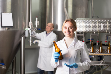 Smiling female brewery worker with bottling machinery