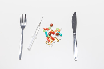 Tabletten, Spritze und Essbesteck