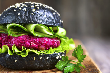 Vegan black burger with beetroot on a cutting board.