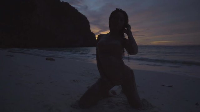 Asian beautiful woman in crochet bikini posing on the beach. 4k video of sexy girl posing on the beach with see and sky background at the outstanding sunset.