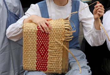 young girl with tapering fingers of the hand creates a straw bag