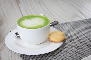 Hot green tea matcha latte in a cup and cookies put aside