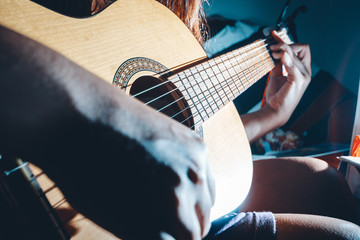 woman's hands playing acoustic guitar, close up