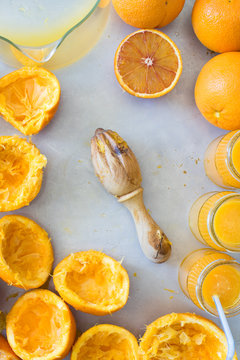 Wooden squeezer, squeezed oranges and fresh orange juice in jars. Selective focus on squeezer.