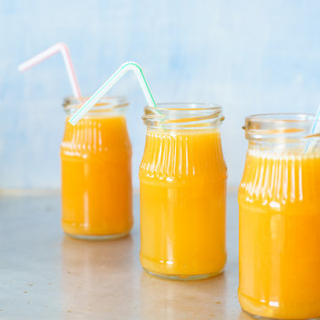 Three jars with freshly squeezed orange juice. Selective focus.