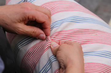 woman while sewing with needle and thread the pillow