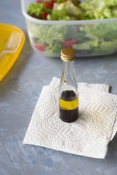 Small bottle with olive oil and balsamic vinegar to  season takeaway salad. Selective focus.