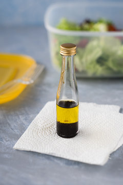Small bottle with olive oil and balsamic vinegar to  season takeaway salad. Selective focus.