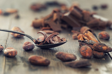 Chocolate pieces with cocoa beans on a wooden table