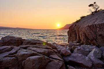 Rock island at sunset in small mediterranean town Brela , Croati