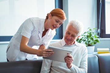 Fototapeta premium Nurse and senior man using a digital tablet