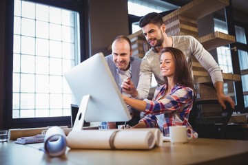Business people discussing over computer in creative office