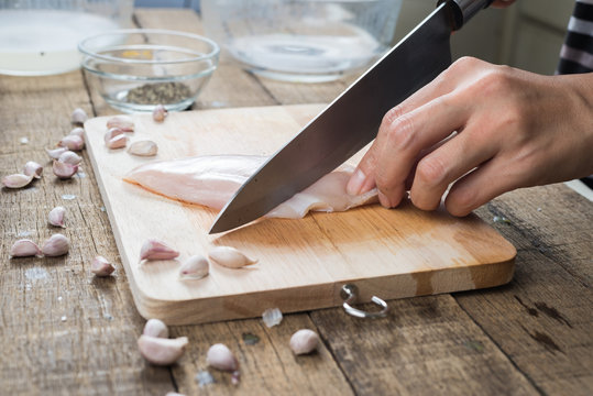 Food series : Closeup of woman hand cutting chicken breast on wooden board
