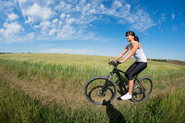Fototapeta premium Mountain biking happy sportive girl relax in meadows sunny countryside