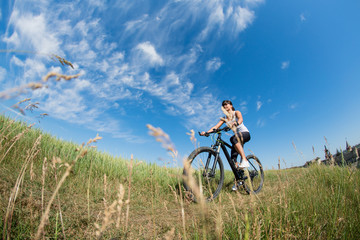 Fototapeta na wymiar Mountain biking happy sportive girl relax in meadows sunny countryside