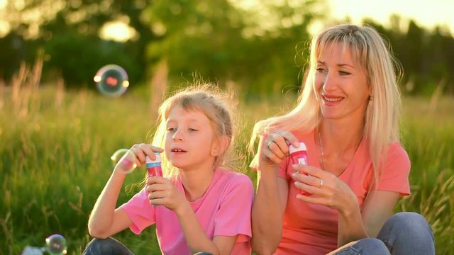 Mother and the child blowing bubbles. Slow motion
