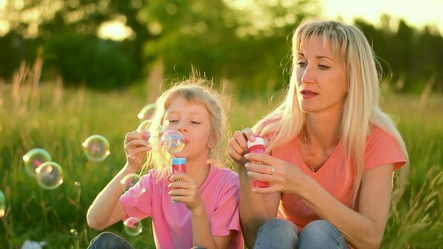 Mother and the child blowing bubbles. Slow motion
