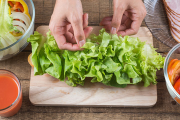 Food series : Making baguette ham sandwich, woman's hands placing lettuce on baguette sandwich