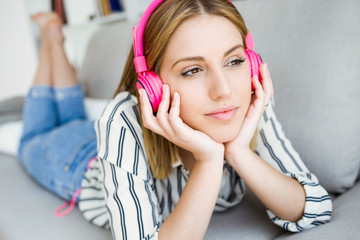 Beautiful young woman listening to music at home.