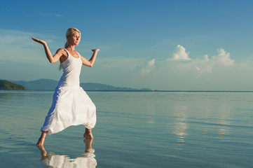 Fototapeta na wymiar Young woman doing yoga at sunset. Girl doing balance practice at the beach. 