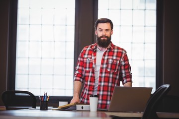 Hipster standing by desk in creative office