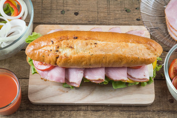 Food series : Baguette ham sandwich on wooden board with tomatoes juice, top view