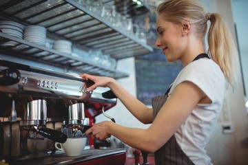 Side view of waitress using coffee maker at cafe
