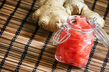 Ginger in a marinade, glass jar, wooden background, selective fo