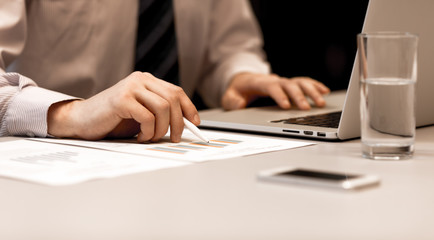 Businessman working on Computer and printed Charts