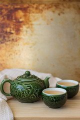 One teapot and two small tea bowls for chinese tea ceremony on wooden table, orange background