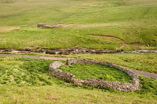Sheepfolds in Upper Coquetdale, with the River Coquet cascading down from the Cheviot Hills in Northumberland