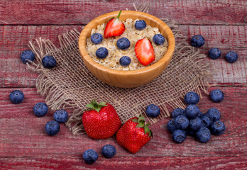 Breakfast with porridge, strawberry and blueberry on a wooden ta
