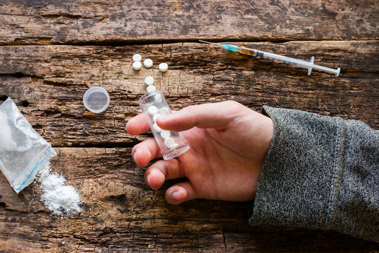 lifeless hand drug addict holding drugs on a wooden background