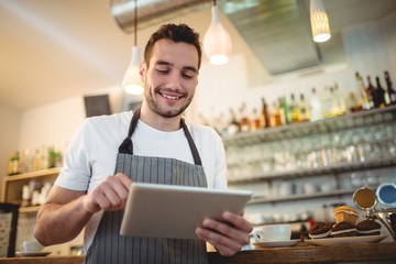 Happy barista using digital tablet at cafe