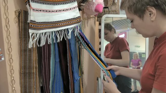 A female customer is scrolling through the rack of waistband. A wide variety of colors and sizes available. Customer picked a blue waistband to try on. 4K UHD video footage.