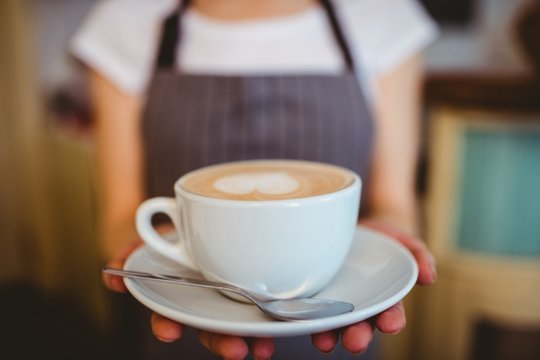 Midsection of barista serving coffee at cafeteria