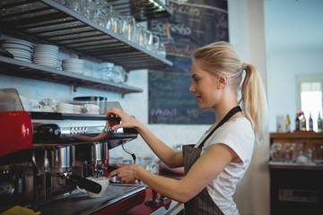 Side view of barista using espresso maker at coffee house