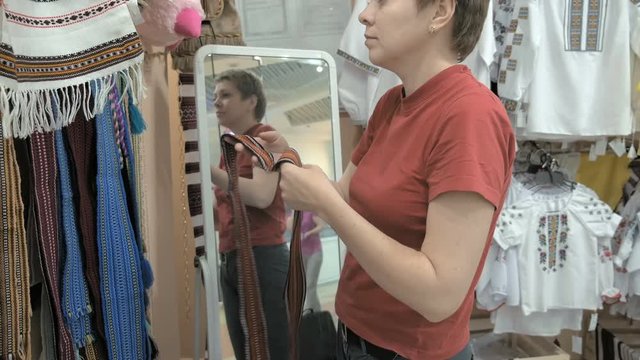 A female customer is scrolling through the rack of waistband. A wide variety of colors and sizes available. Customer picked a blue waistband to try on. 4K UHD video footage.