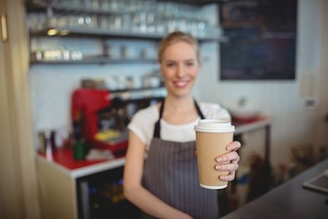 Portrait of barista holding coffee cup at cafe