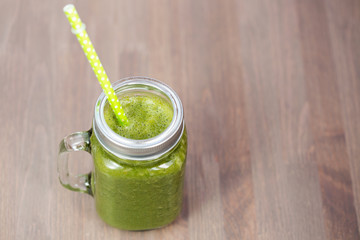 Healthy carrot smoothie in a jar with tube on wooden background. Shallow dof
