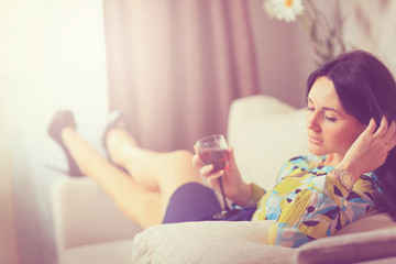 Obraz na płótnie Canvas The girl with a wine glass on a sofa