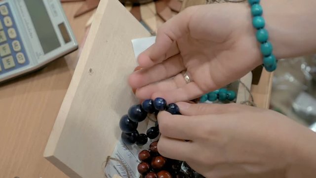 Several bracelets made out of wooden beads. Available in different sizes and colors. A customer is trying the bracelets on, best fit for all ages. 4K UHD video footage.