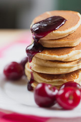 Tasty Pancake with fresh cherries and jam on a white plate. American breakfast