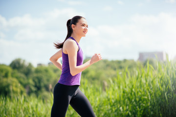 Dreaming, smiling beautiful and attractive woman running in park on sunny day. Sport