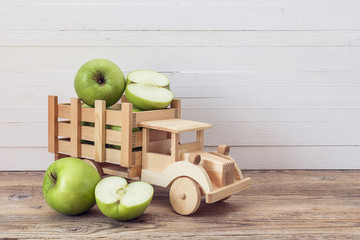 Toy wooden truck with green apples in the back.