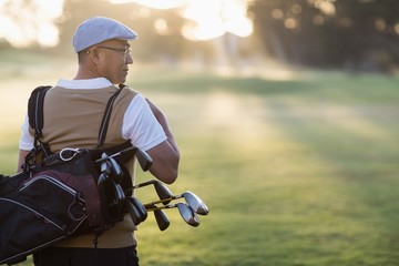 Naklejka premium Rear view of mature man carrying golf bag 