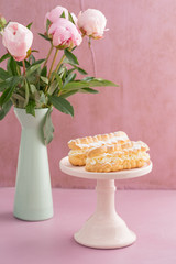 Eclairs with buttercream filling on a pink cake stand